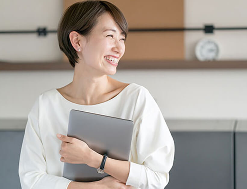 PCを持ち微笑む女性
